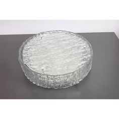 a glass cake plate sitting on top of a black tablecloth covered surface with white frosting