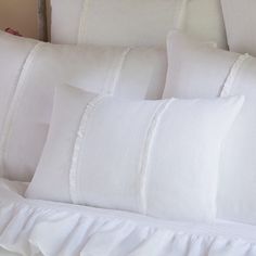 four white pillows with ruffled edges on a bed