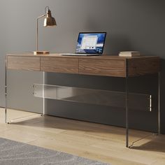 a laptop computer sitting on top of a wooden desk next to a lamp and rug