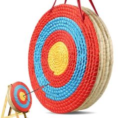 a red, yellow and blue basket with an arrow on it next to a small stool