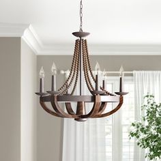 a wooden chandelier hanging from a ceiling in a living room with white curtains