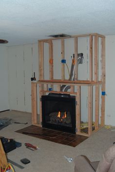 a living room with a fire place in the center and unfinished walls around it,