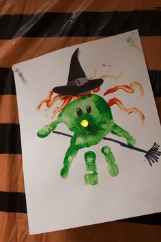 a drawing of a hand with a witch hat holding a broom and glowing green eyes