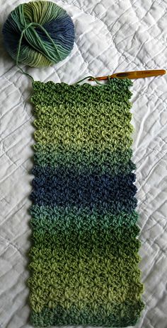 a crocheted blanket with yarn next to it