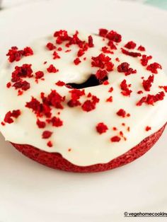 a red velvet donut with white frosting and sprinkles