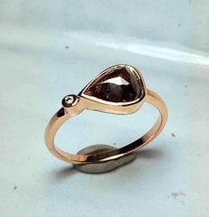 a gold ring with a brown diamond in it's center on a white surface