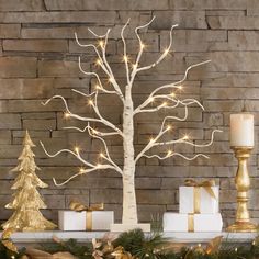 a lighted christmas tree next to presents in front of a brick wall with gold and white decorations