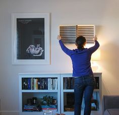 a woman standing in front of a bookshelf holding her arms up to the ceiling