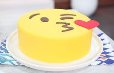 there is a yellow cake with a red heart on the top and an emoticive face