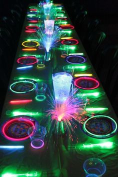 a long table with many different colored lights on it and some drinks in the middle