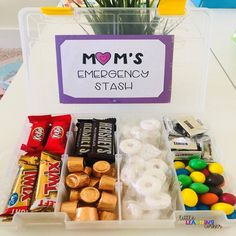 a plastic container filled with candy and candies next to a sign that says mom's emergency stash