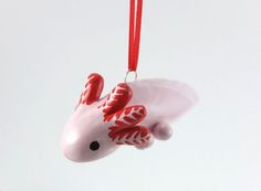 a red and white ornament hanging from a string on a hook with an animal design