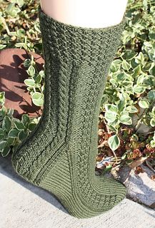 a pair of green socks sitting on top of a cement slab next to some plants