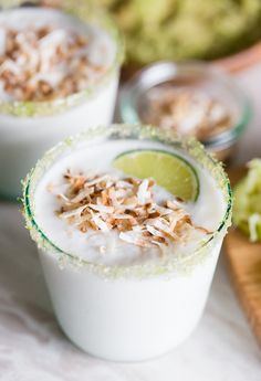 a close up of a drink in a glass with coconut and limes around it