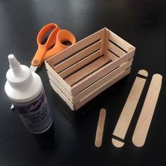 scissors, glue and wooden strips are sitting on a table next to an empty container