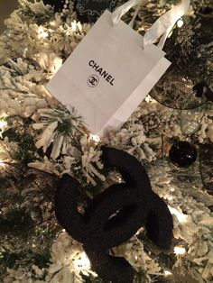 a chanel bag sitting on top of a christmas tree next to a black and white ornament