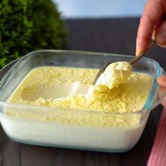 a person scooping something out of a dish with a spoon in it on a table