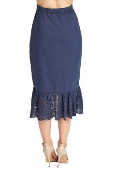 Back view of model wearing navy cotton eyelet ruffle hem skirt. Summer Bottoms With Ruffle Hem And Midi Length, Spring Midi Bottoms With Ruffle Hem, Vacation Ruffled Midi Skirt, Cotton Midi Length Bottoms For Summer, Chic Summer Skirt With Cutwork Hem, Vacation Midi Ruffled Skirt, Cotton Midi Bottoms For Vacation, Asymmetrical Skirt With Lace Trim For Summer, Cotton Midi Skirt With Ruffles