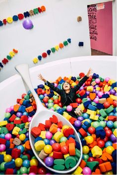 a woman laying on top of a large bowl filled with lots of colorful candies