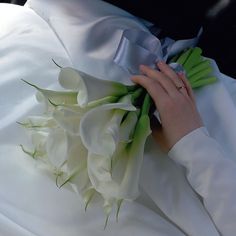 a bride's bouquet is being held by her hands on the back of her wedding dress