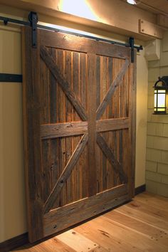 an open wooden door in a room with a light on the wall and a lamp hanging above it