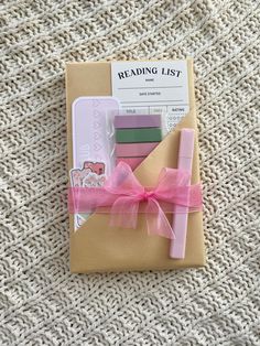 a pink bow is tied on top of a brown book with writing supplies in it