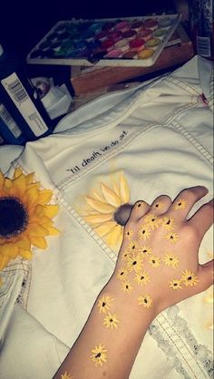 a person with sunflowers painted on their body and hand next to a flower