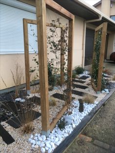 an outdoor area with rocks and plants on the ground, along side a building in front of it