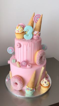 a pink cake with donuts and ice cream on top