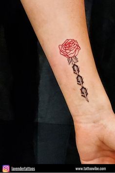 a small rose tattoo on the wrist with stars around it and an arrow in the middle