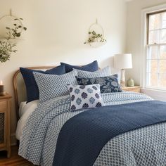 a bed with blue and white comforters in a bedroom next to a window,