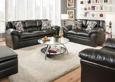 a living room filled with black leather couches and chairs next to a white rug