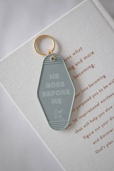 a keychain with the words he goes before me written on it