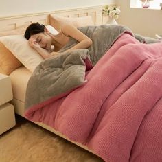 a woman laying on top of a bed under a blanket