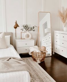 a bedroom with white furniture and a large mirror