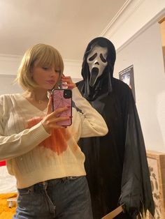 a woman taking a selfie in front of a halloween costume with a ghost behind her