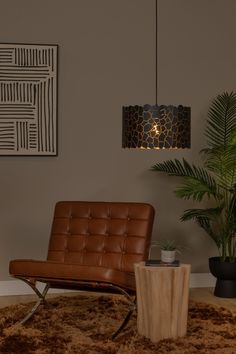 a brown chair sitting on top of a rug next to a wooden table and potted plant