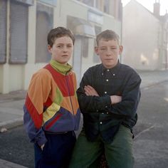 two boys standing next to each other on the street