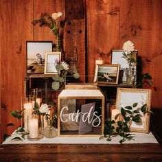 a table topped with framed pictures and flowers on top of a wooden table next to candles