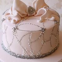 a white cake decorated with pearls and bows