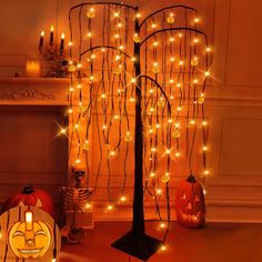 halloween decorations with pumpkins and lights in front of a tree decorated with fake branches