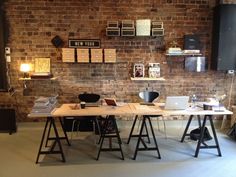 a brick wall in an office with two desks