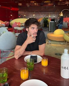 a man sitting at a table with some drinks in front of him and looking to the side