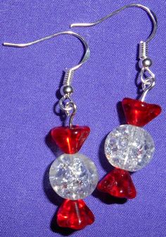 two red and clear glass beads hanging from silver earwires on a purple background