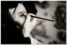 a woman is getting her make up done in black and white with an eyeliner brush