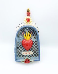 a small blue box with a red heart and yellow flowers on the top, sitting in front of a white background