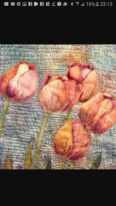 three pink flowers are in the middle of a quilted piece of fabric with green stems