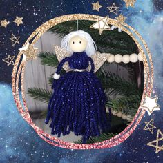 a christmas ornament with a blue dress and white hair on it, surrounded by stars