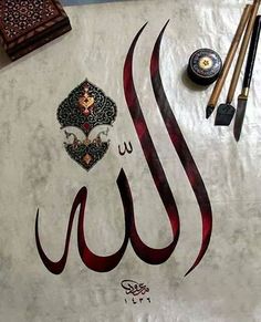 an arabic calligraphy is displayed on a table with other art supplies and items around it