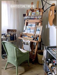 an artist's easel in the corner of a room filled with art supplies